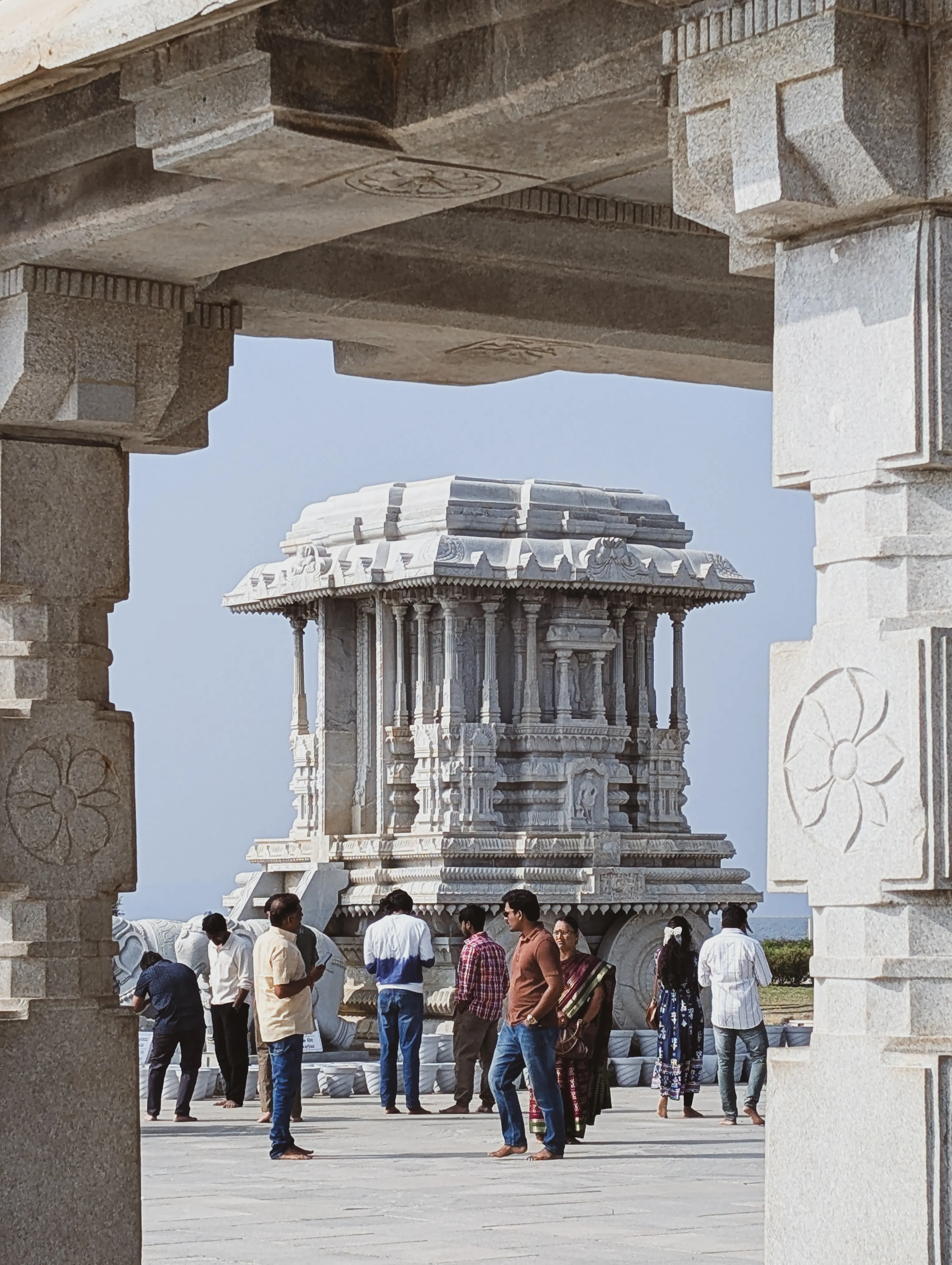 People inside a frame in front of a stone chariot